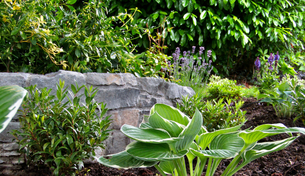 Design ideas for a beach style side partial sun garden in Vancouver with a retaining wall and mulch.