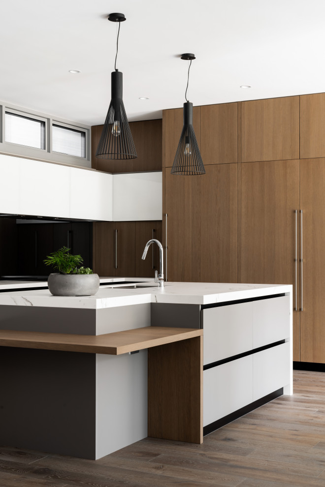 This is an example of a contemporary kitchen in Other with an undermount sink, flat-panel cabinets, medium wood cabinets, panelled appliances, medium hardwood floors, with island, grey floor and white benchtop.