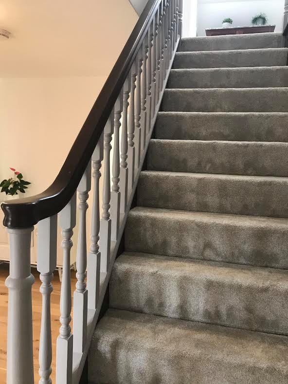 Photo of a small transitional carpeted straight staircase in Hampshire with wood risers, wood railing and panelled walls.