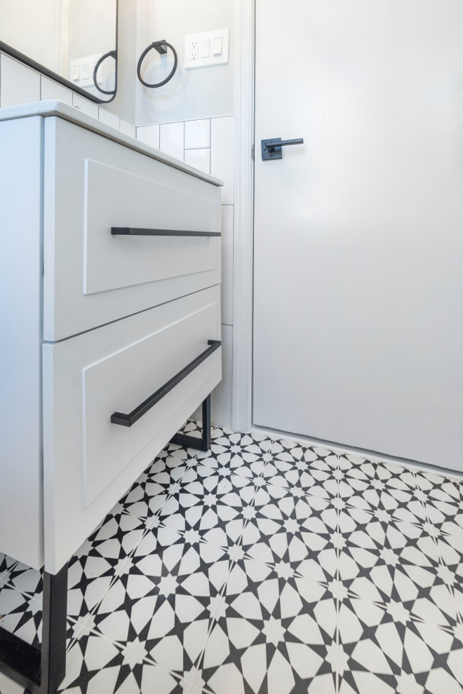 Photo of a small midcentury shower room bathroom in DC Metro with freestanding cabinets, white cabinets, an alcove shower, a two-piece toilet, white tiles, metro tiles, grey walls, porcelain flooring, a built-in sink, solid surface worktops, black floors, a sliding door, white worktops, a wall niche, a single sink, a freestanding vanity unit and wainscoting.
