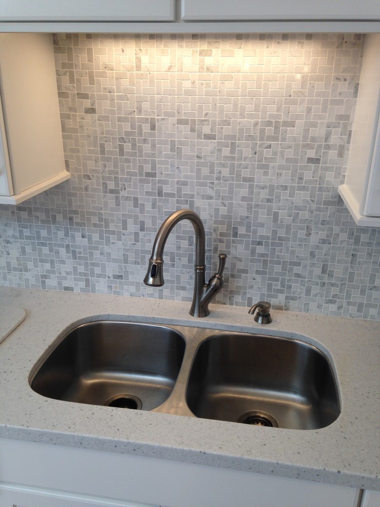 Eat-in kitchen - mid-sized coastal l-shaped eat-in kitchen idea with an undermount sink, beaded inset cabinets, white cabinets, solid surface countertops, gray backsplash, mosaic tile backsplash, white appliances and a peninsula