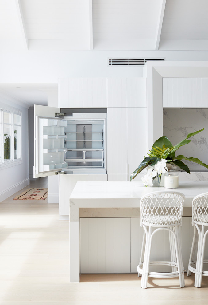 Design ideas for a large beach style galley eat-in kitchen in Sydney with an undermount sink, white cabinets, white splashback, panelled appliances, with island and white benchtop.