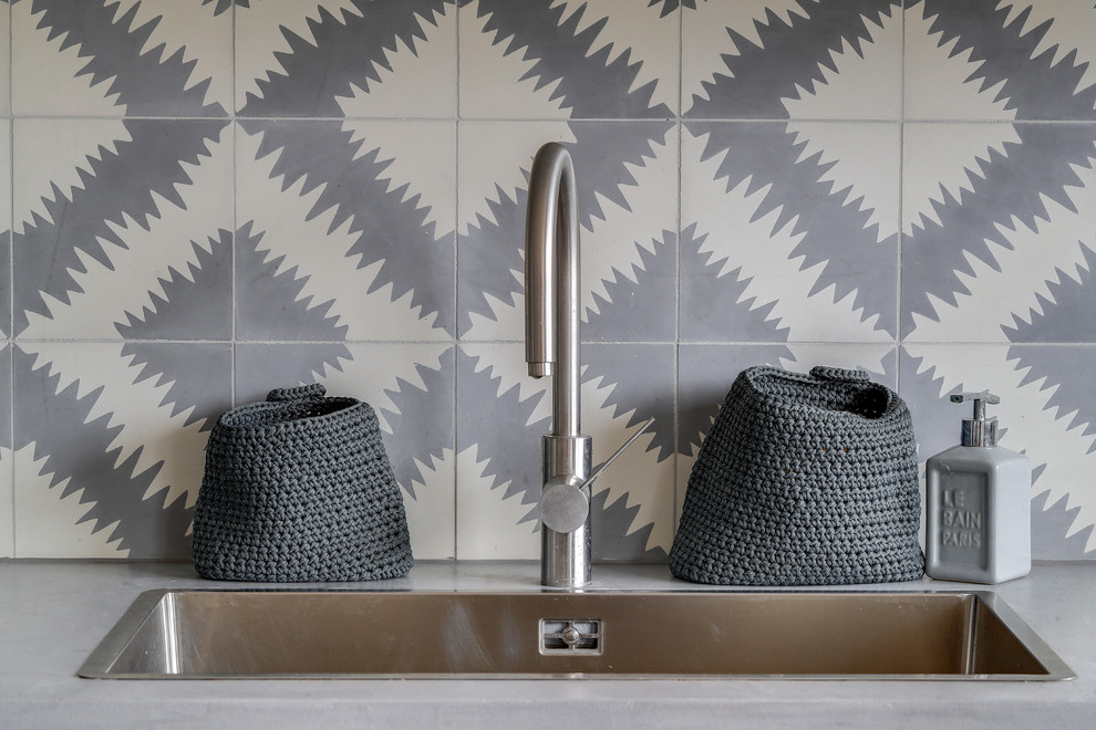 Inspiration pour une grande cuisine américaine design en L avec un évier encastré, un placard à porte affleurante, des portes de placard grises, un plan de travail en béton, une crédence grise, une crédence en carreau de ciment, un électroménager en acier inoxydable, un sol en bois brun, îlot, un sol marron et un plan de travail gris.