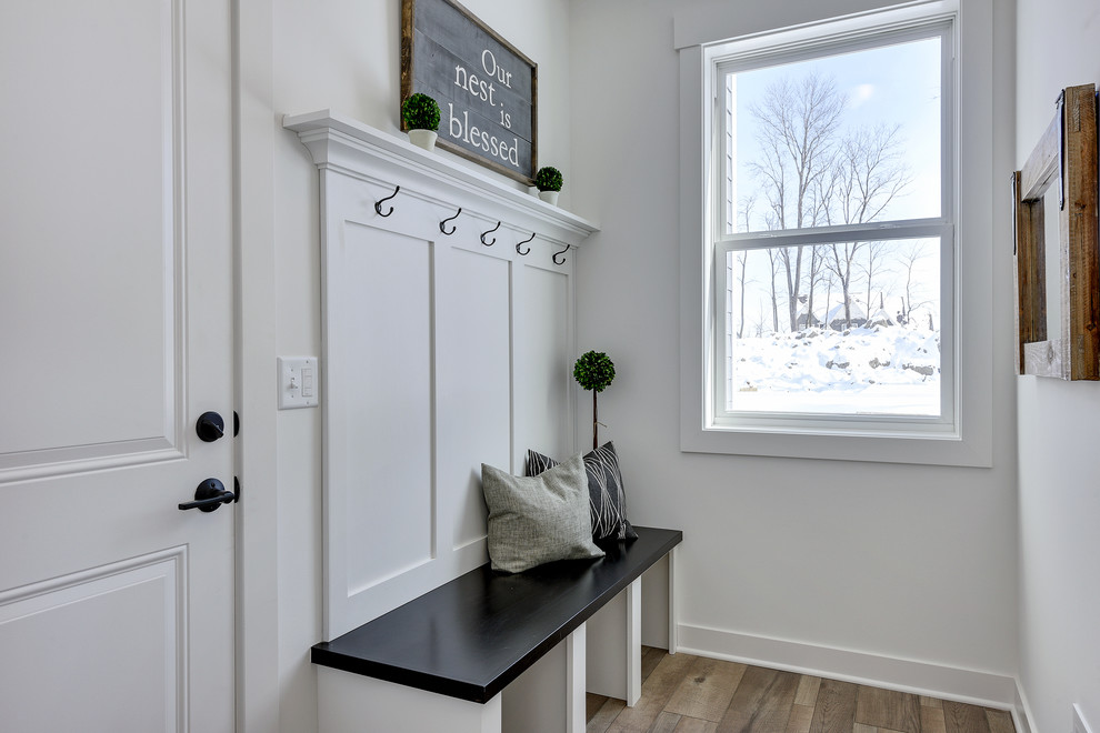 Photo of a mid-sized country mudroom in Minneapolis with white walls, laminate floors, a single front door, a white front door and grey floor.