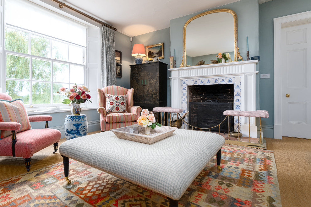 На фото: гостиная комната в классическом стиле с синими стенами, ковровым покрытием, стандартным камином, фасадом камина из плитки и коричневым полом