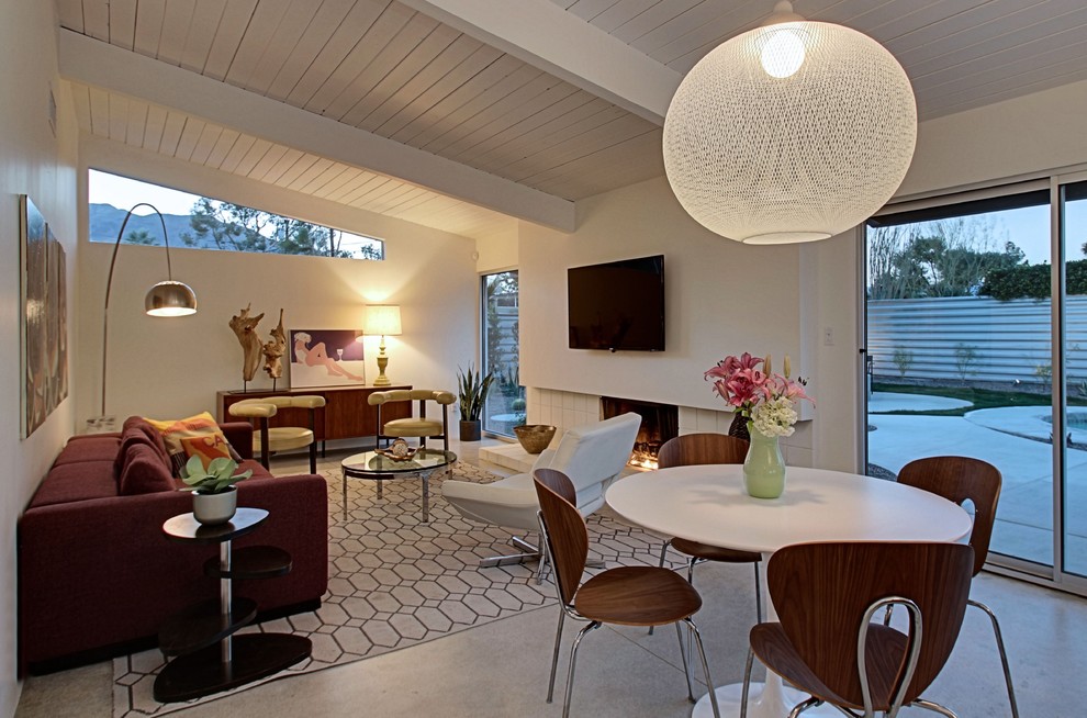 Mid-sized midcentury open concept family room in Los Angeles with white walls, concrete floors, a standard fireplace, a tile fireplace surround and a wall-mounted tv.