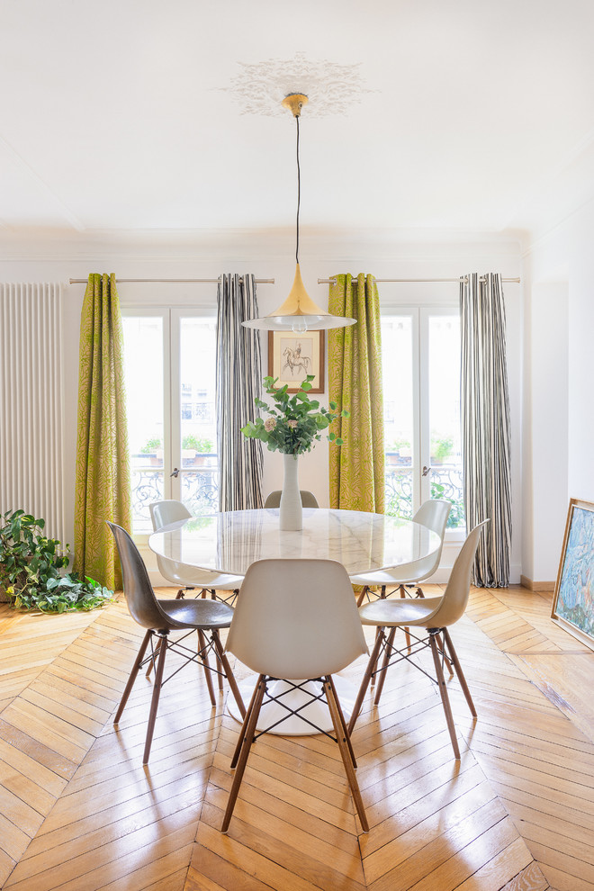 Photo of a contemporary dining room in Paris with white walls and medium hardwood floors.