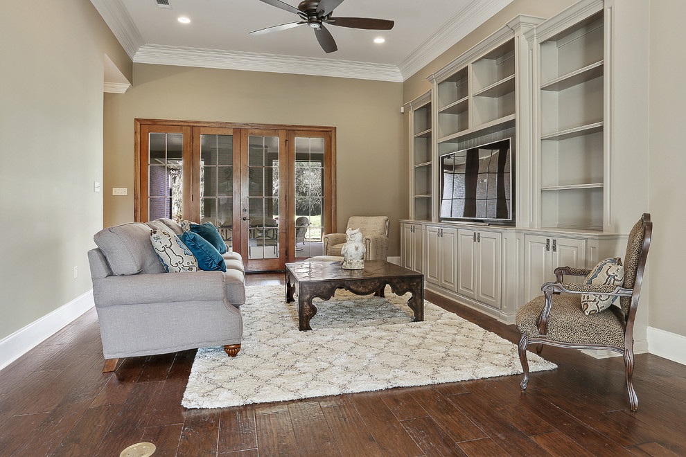 Photo of a mid-sized transitional enclosed family room in New Orleans with a library, beige walls, bamboo floors, no fireplace, a plaster fireplace surround and a built-in media wall.