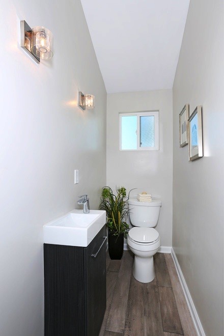 Inspiration for a small beach style powder room in Orange County with flat-panel cabinets, black cabinets, a one-piece toilet, white tile, stone slab, grey walls, dark hardwood floors, a drop-in sink and solid surface benchtops.