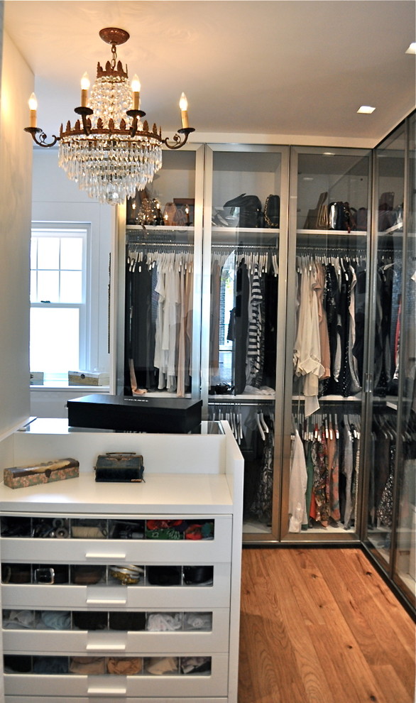 This is an example of a large contemporary women's walk-in wardrobe in Other with white cabinets, light hardwood floors and flat-panel cabinets.
