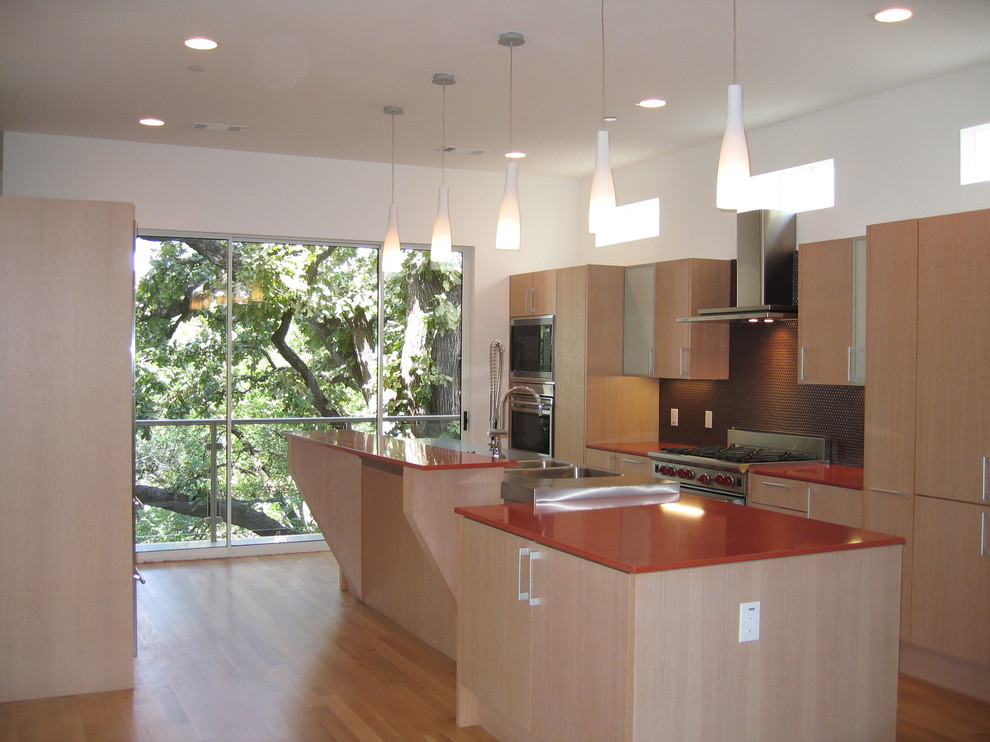 This is an example of a small modern galley open plan kitchen in Dallas with a double-bowl sink, flat-panel cabinets, light wood cabinets, quartz benchtops, brown splashback, mosaic tile splashback, stainless steel appliances, light hardwood floors, with island, beige floor and orange benchtop.