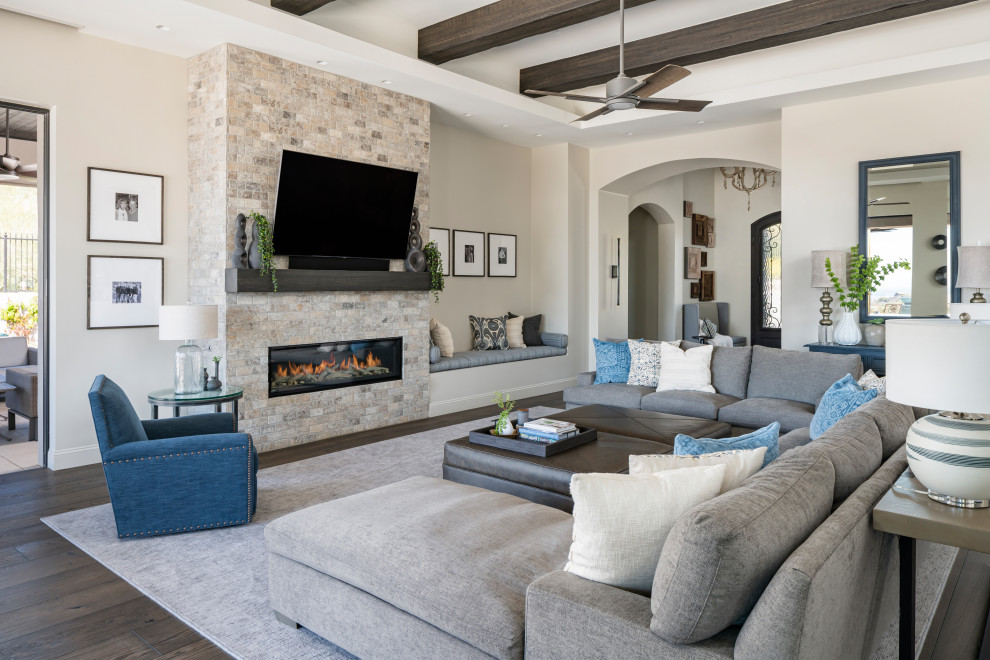 Inspiration for an expansive transitional open concept living room in Phoenix with grey walls, dark hardwood floors, a standard fireplace, a stone fireplace surround, a wall-mounted tv, brown floor and exposed beam.