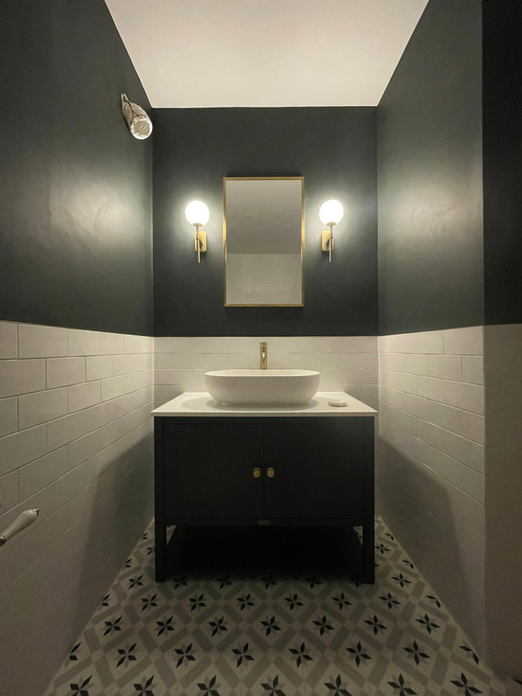 Photo of a medium sized classic cloakroom in London with flat-panel cabinets, black cabinets, grey walls, porcelain flooring, a console sink, quartz worktops, multi-coloured floors, white worktops and a freestanding vanity unit.