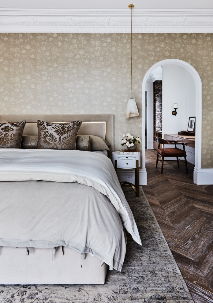 Immagine di una camera matrimoniale classica con pareti beige, pavimento in legno massello medio, pavimento marrone e carta da parati