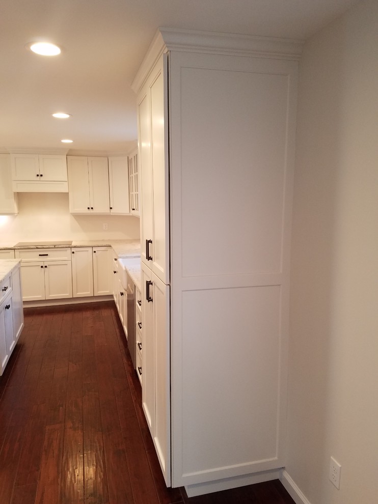 Mid-sized transitional l-shaped dark wood floor and brown floor eat-in kitchen photo with a farmhouse sink, shaker cabinets, white cabinets, granite countertops, white backsplash, subway tile backsplash, stainless steel appliances and an island