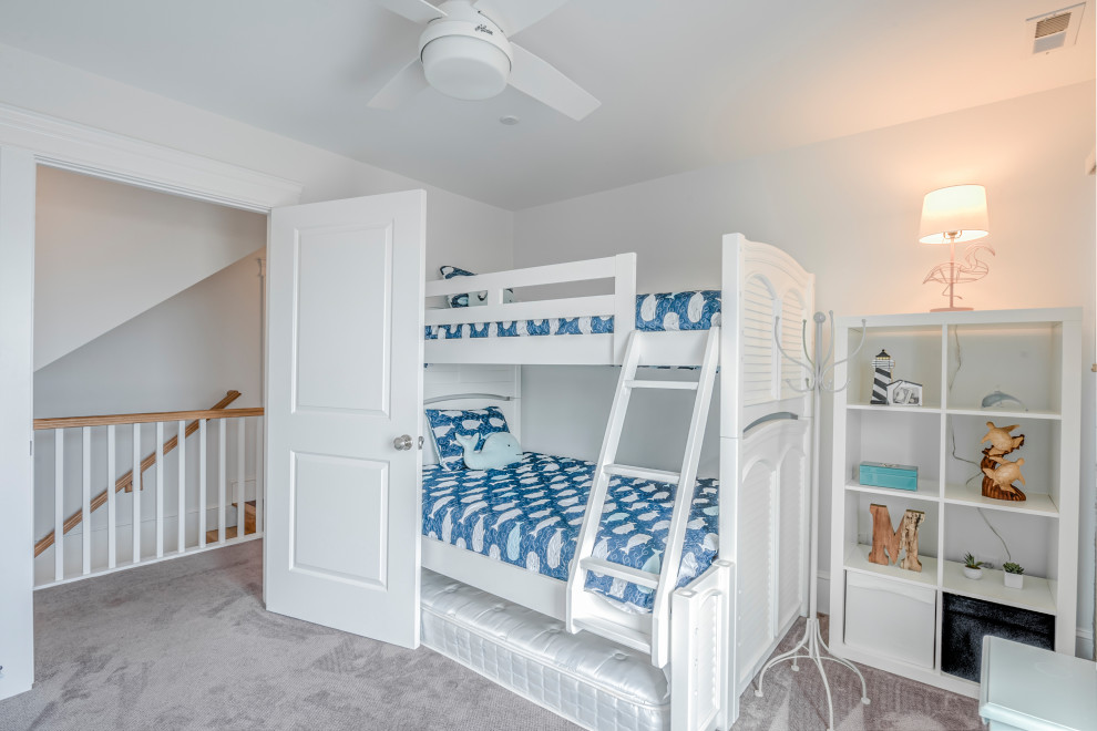 Photo of a mid-sized beach style gender-neutral kids' bedroom for kids 4-10 years old in Other with white walls, carpet and beige floor.
