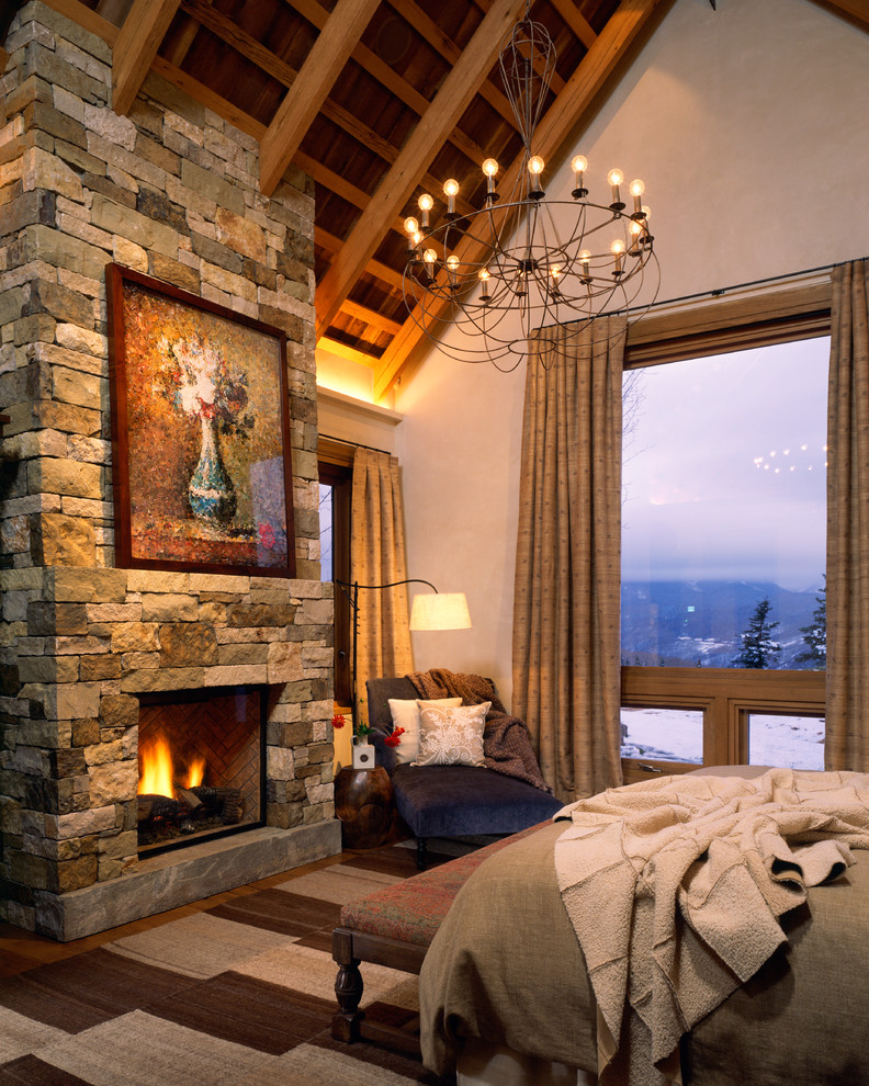 This is an example of a large country master bedroom in Denver with a standard fireplace, a stone fireplace surround and white walls.