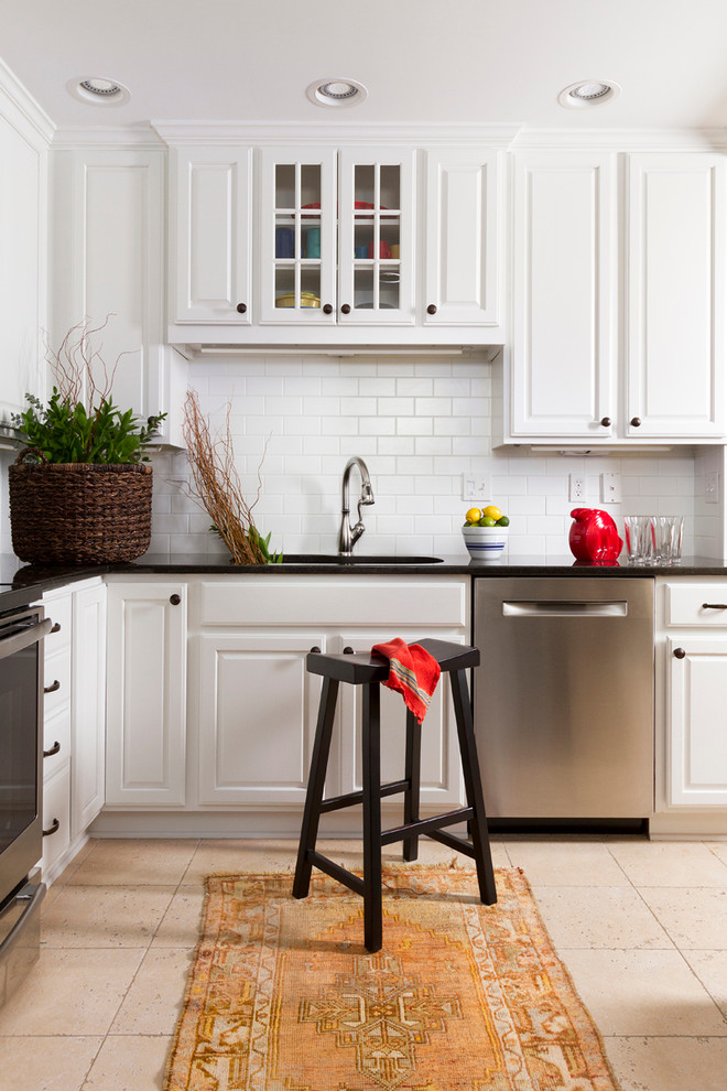 Photo of a traditional l-shaped kitchen in Minneapolis with an undermount sink, raised-panel cabinets, white cabinets, white splashback, subway tile splashback and stainless steel appliances.