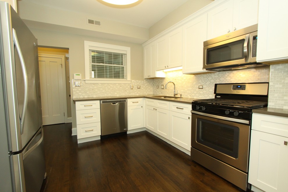 Enclosed kitchen - small transitional u-shaped dark wood floor and brown floor enclosed kitchen idea in Chicago with an undermount sink, recessed-panel cabinets, white cabinets, quartz countertops, white backsplash, mosaic tile backsplash, stainless steel appliances, no island and gray countertops