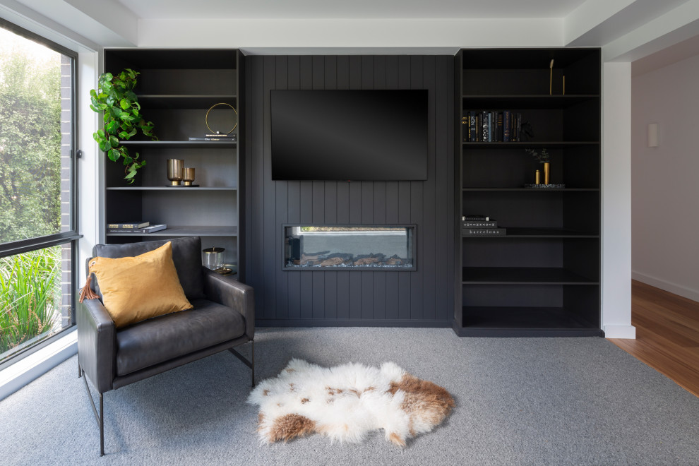 Réalisation d'une petite salle de séjour minimaliste ouverte avec une bibliothèque ou un coin lecture, un mur noir, moquette, une cheminée ribbon, un téléviseur encastré et un sol gris.