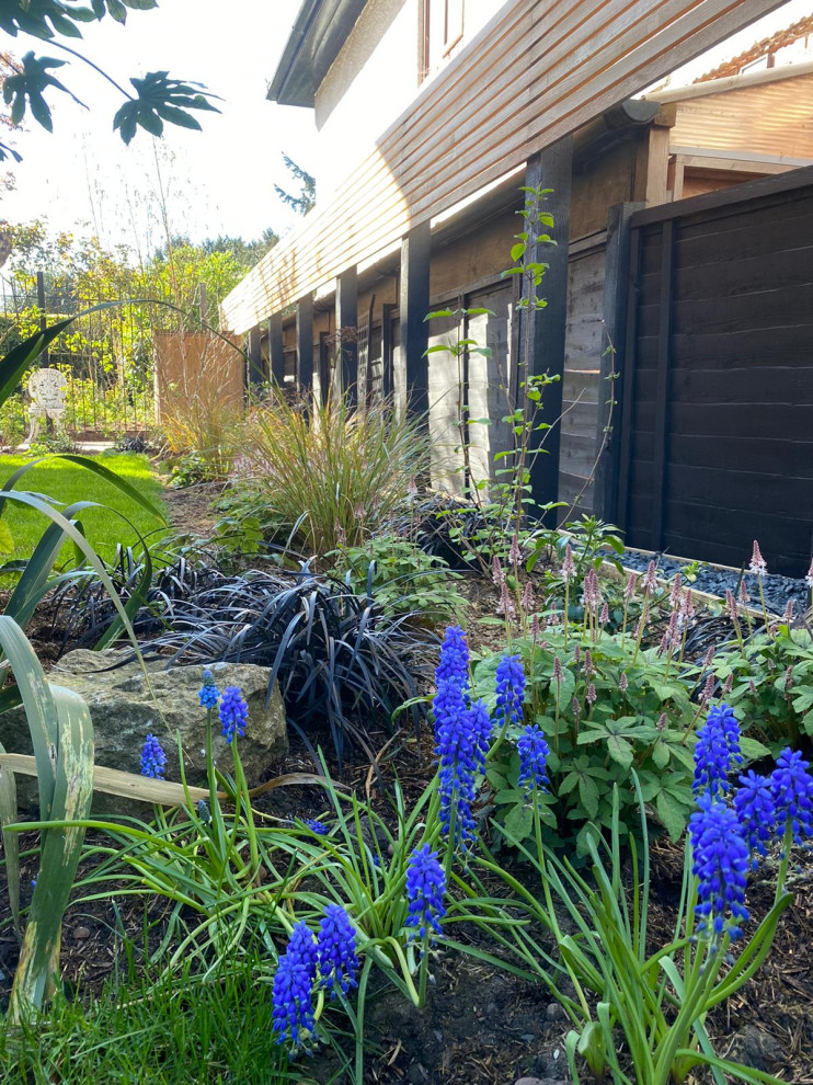 На фото: участок и сад на боковом дворе в современном стиле с дорожками, полуденной тенью и с деревянным забором