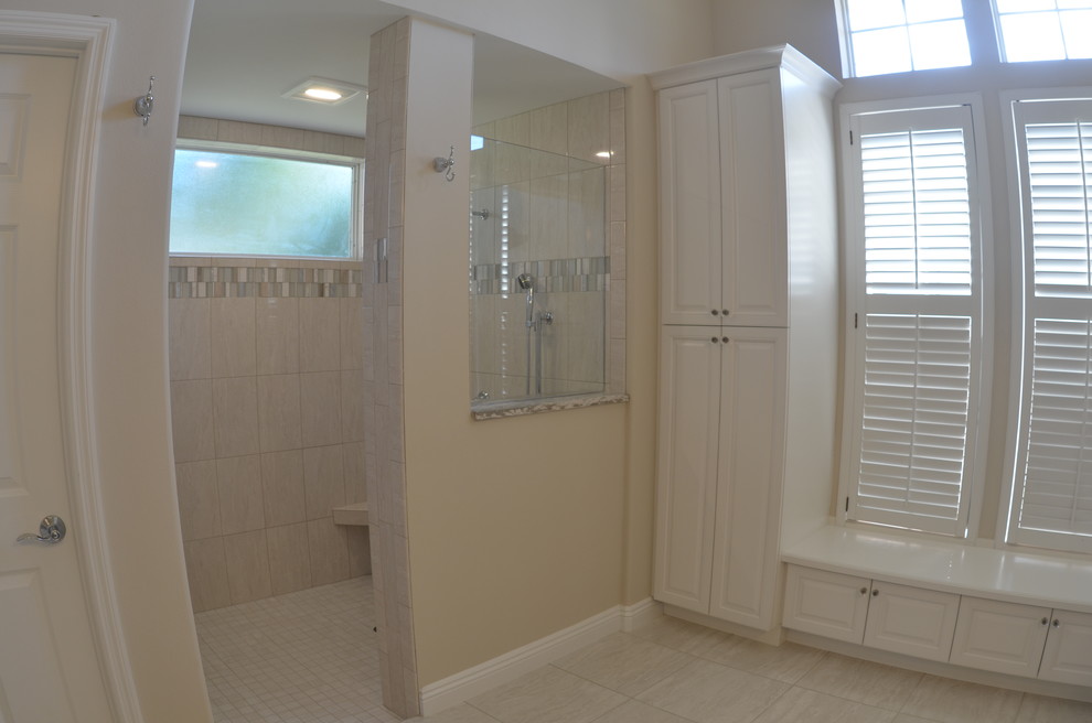 Design ideas for a mid-sized beach style 3/4 bathroom in Orange County with recessed-panel cabinets, white cabinets, an alcove shower, a one-piece toilet, beige walls, travertine floors, an undermount sink and granite benchtops.