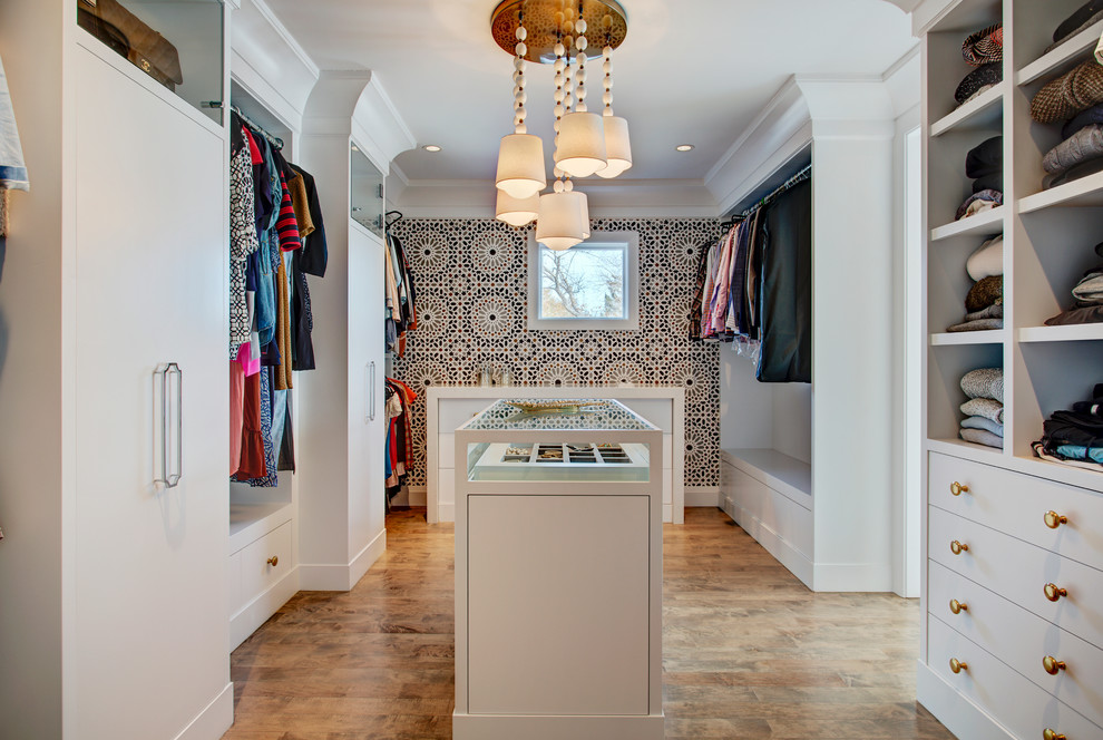 Design ideas for a transitional gender-neutral walk-in wardrobe in Calgary with flat-panel cabinets, white cabinets, brown floor and medium hardwood floors.
