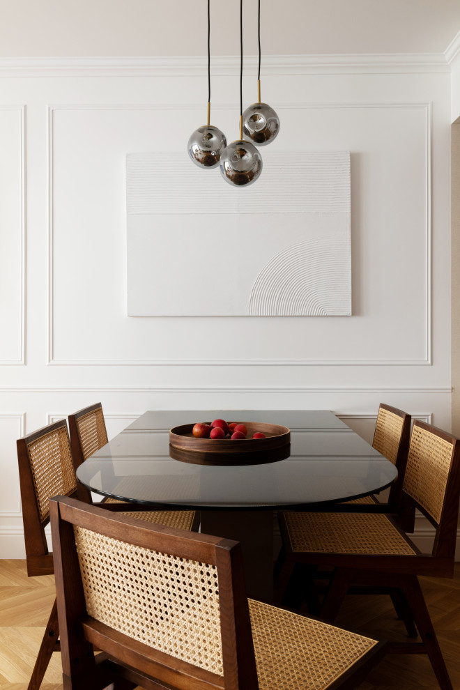 Cette image montre une salle à manger ouverte sur le salon traditionnelle de taille moyenne avec un mur blanc, parquet clair, un sol marron, boiseries et éclairage.