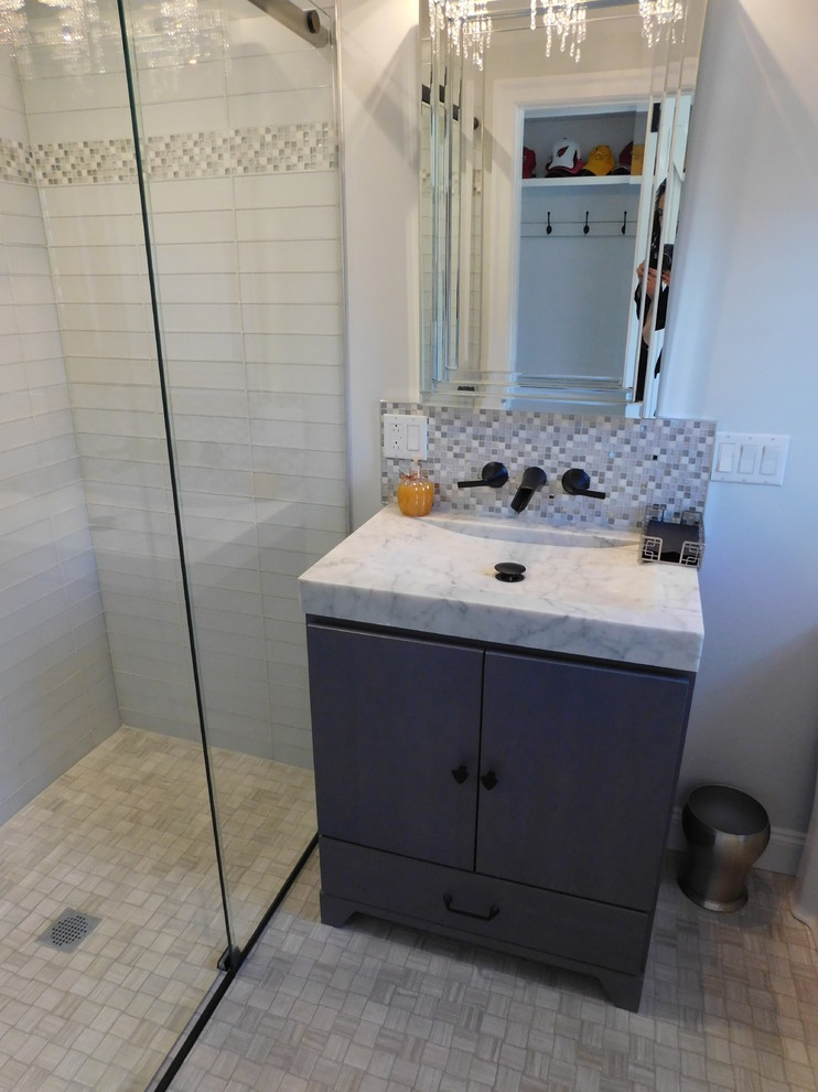 Inspiration for a mid-sized modern 3/4 bathroom in New York with flat-panel cabinets, grey cabinets, a curbless shower, a two-piece toilet, gray tile, glass tile, grey walls, mosaic tile floors, a trough sink, quartzite benchtops, grey floor, a hinged shower door and white benchtops.