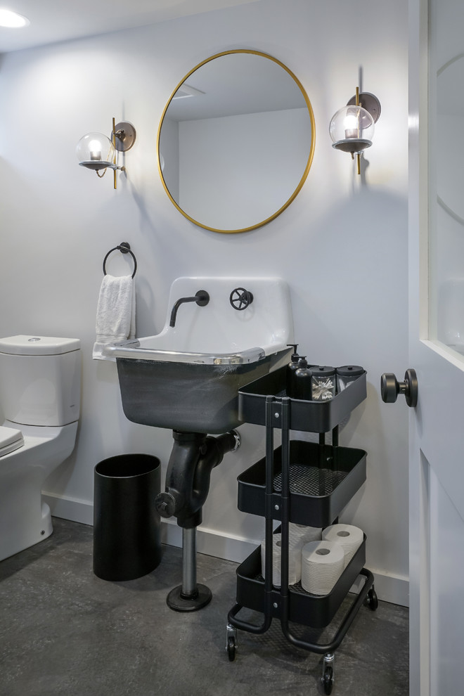 Industrial powder room in Portland with a two-piece toilet, white walls, concrete floors, a wall-mount sink and grey floor.