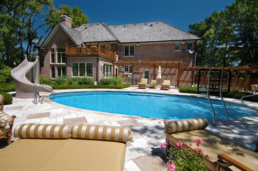 Photo of a mid-sized modern backyard custom-shaped natural pool in Chicago with a water slide and natural stone pavers.