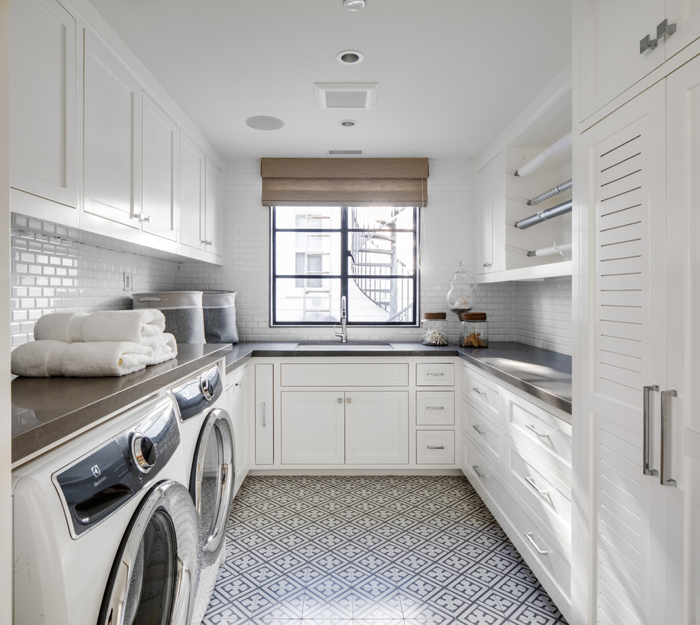 Beach style u-shaped dedicated laundry room in Orange County with shaker cabinets, white cabinets, white walls, a side-by-side washer and dryer, multi-coloured floor and grey benchtop.