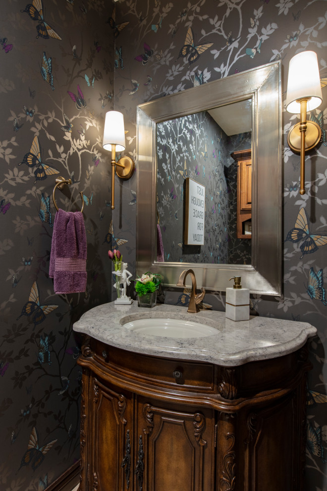 This is an example of a small transitional powder room in Oklahoma City with furniture-like cabinets, medium wood cabinets, multi-coloured walls, engineered quartz benchtops, multi-coloured benchtops, a freestanding vanity and wallpaper.
