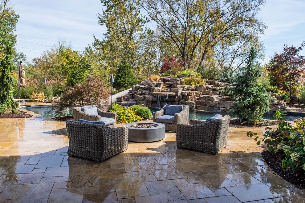 Design ideas for a large tropical backyard patio in St Louis with natural stone pavers, a fire feature and no cover.
