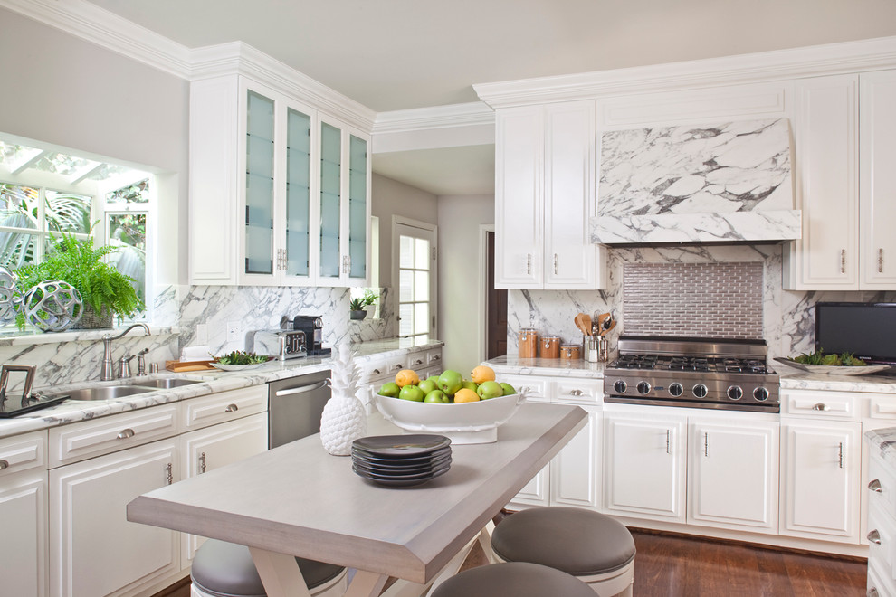 Inspiration for a mid-sized transitional u-shaped separate kitchen in Los Angeles with glass-front cabinets, marble benchtops, marble splashback, a double-bowl sink, white cabinets, white splashback, stainless steel appliances, dark hardwood floors, with island and brown floor.