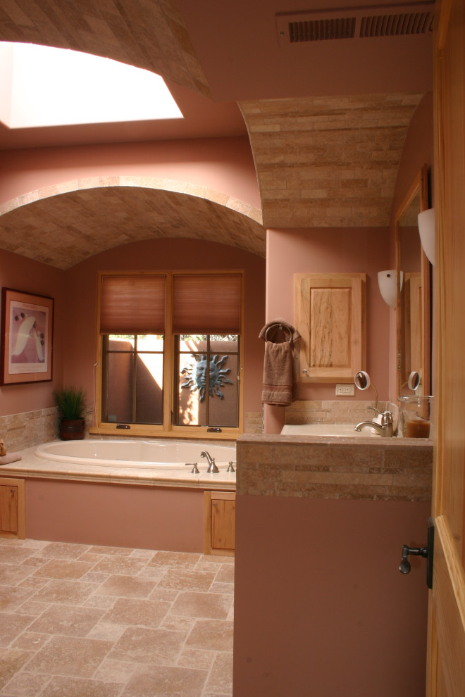 Photo of a large master bathroom in Albuquerque with a drop-in tub, beige tile, stone tile, brown walls, porcelain floors, beige floor, a single vanity and a built-in vanity.