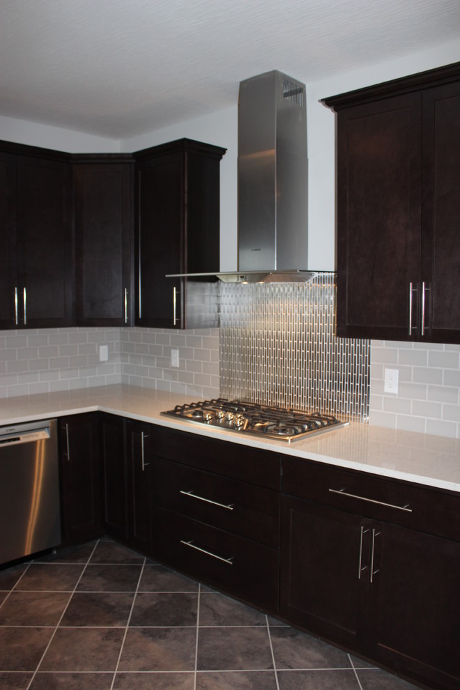 Example of a large eclectic u-shaped travertine floor open concept kitchen design in Columbus with an undermount sink, recessed-panel cabinets, dark wood cabinets, limestone countertops, metallic backsplash, metal backsplash, stainless steel appliances and an island