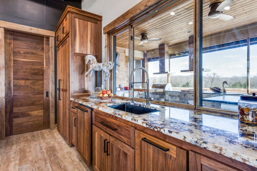 This is an example of a mid-sized traditional galley kitchen in Austin with an undermount sink, flat-panel cabinets, medium wood cabinets, granite benchtops, black splashback, porcelain splashback, panelled appliances, vinyl floors, multiple islands, beige floor, beige benchtop and coffered.
