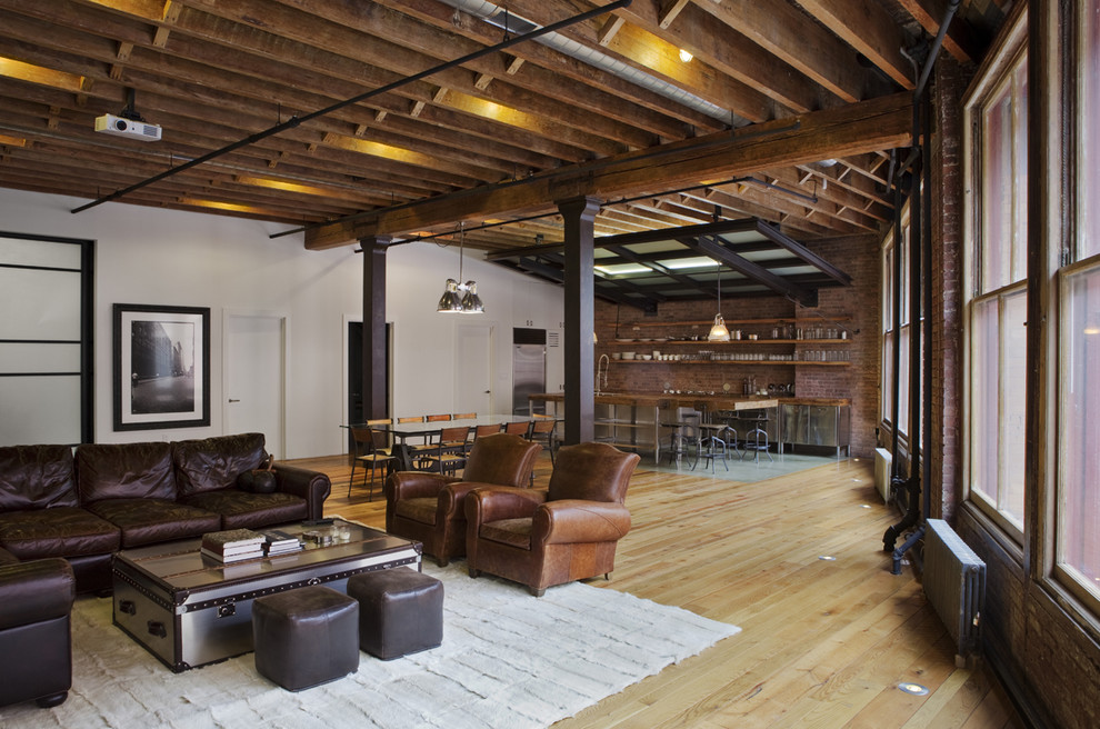 Photo of a large industrial open concept family room in New York with multi-coloured walls and light hardwood floors.