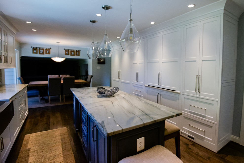 Example of a large transitional u-shaped medium tone wood floor and brown floor eat-in kitchen design in DC Metro with a farmhouse sink, recessed-panel cabinets, white cabinets, marble countertops, stainless steel appliances, an island, gray backsplash and porcelain backsplash