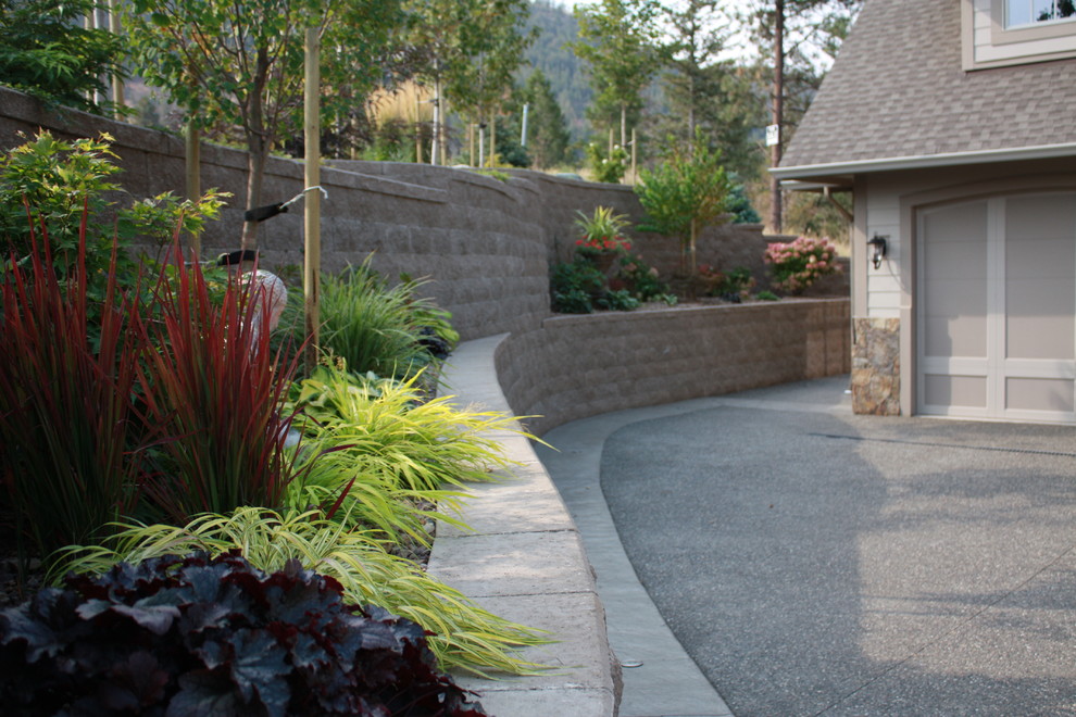 This is an example of a large country full sun driveway in Vancouver with a retaining wall and gravel.