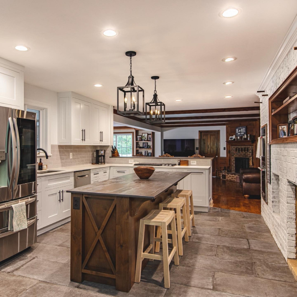 Photo of a large country l-shaped eat-in kitchen in DC Metro with a single-bowl sink, shaker cabinets, distressed cabinets, quartz benchtops, grey splashback, ceramic splashback, stainless steel appliances, cement tiles, with island, grey floor and brown benchtop.