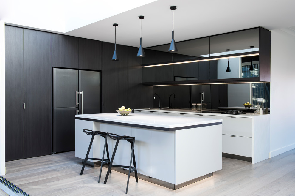 Design ideas for a mid-sized contemporary l-shaped eat-in kitchen in Sydney with a drop-in sink, flat-panel cabinets, black cabinets, quartz benchtops, metallic splashback, mirror splashback, black appliances, light hardwood floors, with island and beige floor.