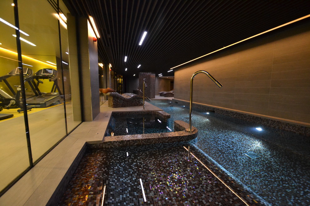 This is an example of a mid-sized contemporary indoor pool in London with a pool house.