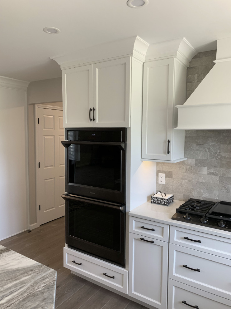 Inspiration for a large transitional l-shaped vinyl floor and gray floor eat-in kitchen remodel with an undermount sink, recessed-panel cabinets, white cabinets, quartz countertops, gray backsplash, ceramic backsplash, stainless steel appliances, an island and white countertops