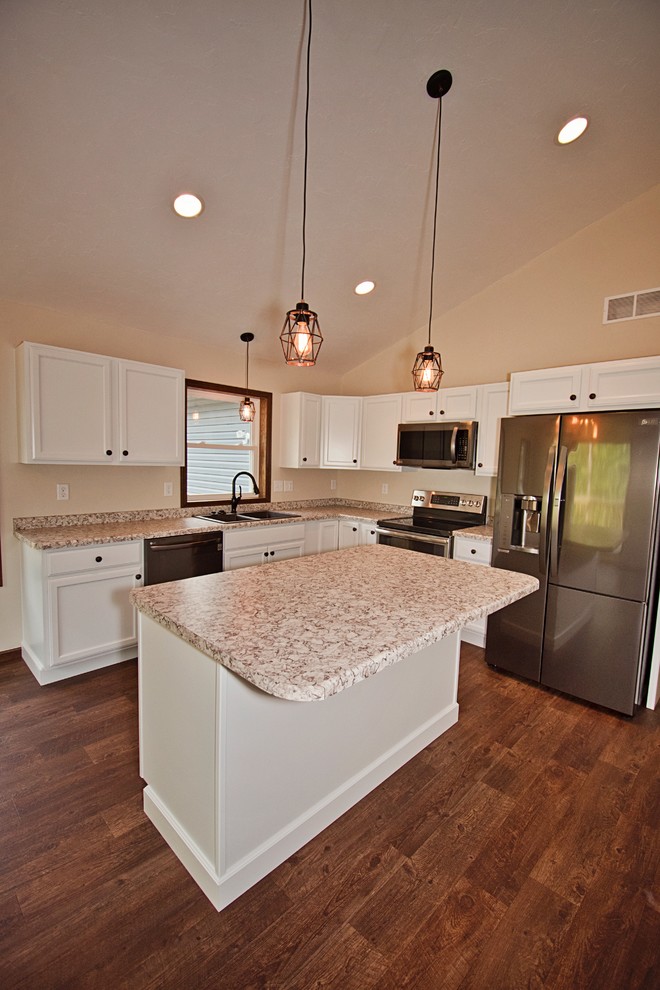 Open concept kitchen - mid-sized transitional l-shaped medium tone wood floor and brown floor open concept kitchen idea with a double-bowl sink, recessed-panel cabinets, white cabinets, laminate countertops, stainless steel appliances, an island and beige countertops