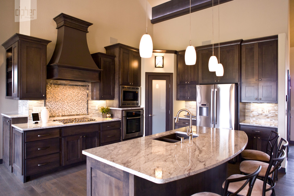 Mid-sized transitional l-shaped dark wood floor and brown floor open concept kitchen photo with an undermount sink, dark wood cabinets, multicolored backsplash, stainless steel appliances, gray walls, an island, raised-panel cabinets, granite countertops and mosaic tile backsplash