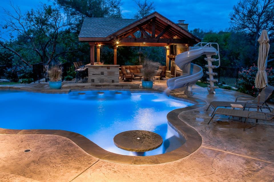 Design ideas for a large tropical backyard custom-shaped pool in Dallas with a water slide and natural stone pavers.