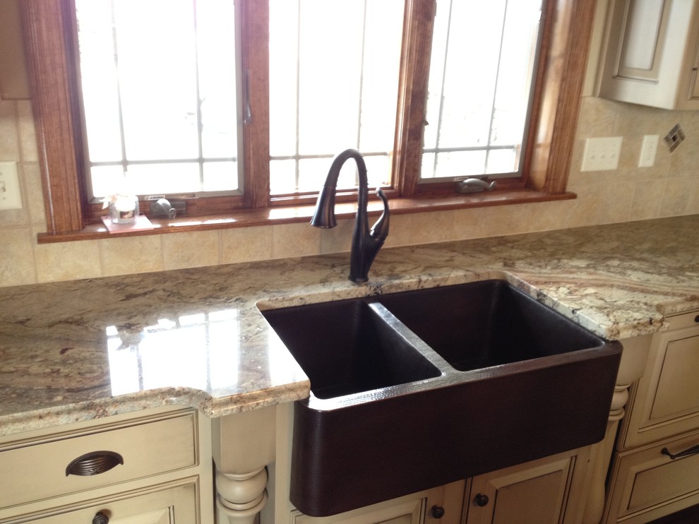 Mid-sized u-shaped eat-in kitchen photo with a farmhouse sink, distressed cabinets, beige backsplash, ceramic backsplash and paneled appliances