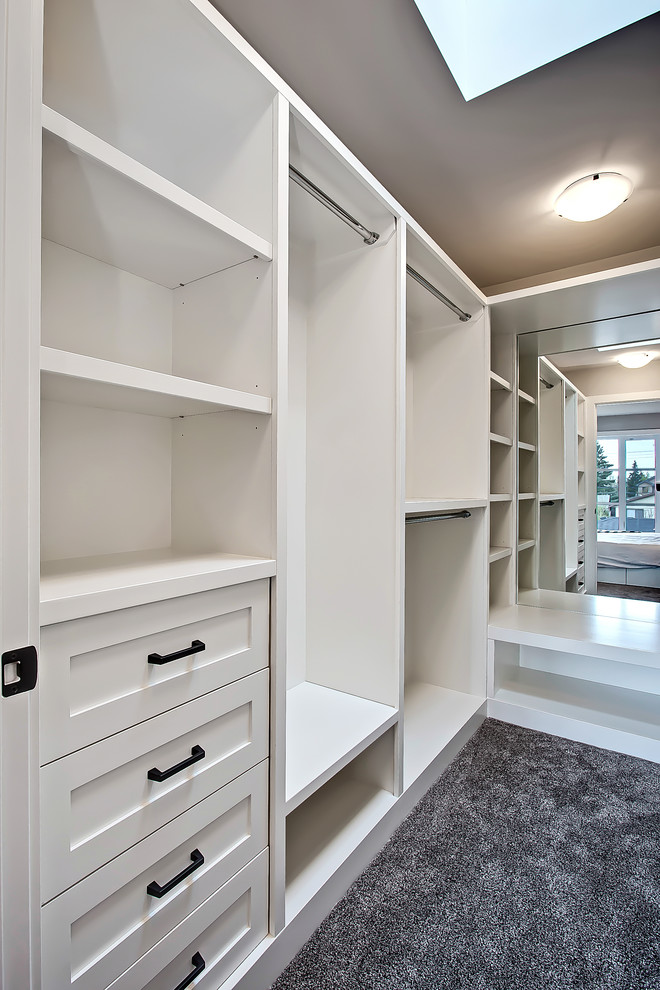 This is an example of a mid-sized transitional gender-neutral walk-in wardrobe in Calgary with shaker cabinets, white cabinets and carpet.